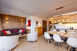 A modern living room with a sofa, chairs, and a dining table set for six. - Apartment La Foret (Riddes)