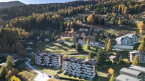 Zona residencial con varios edificios de apartamentos, rodeada de colinas boscosas y un cielo despejado.