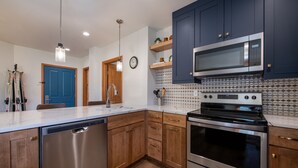 A modern kitchen with stainless steel appliances, wooden cabinets, and a tiled backsplash.