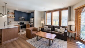 A modern kitchen with dark blue cabinets, stainless steel appliances, and a wooden island.