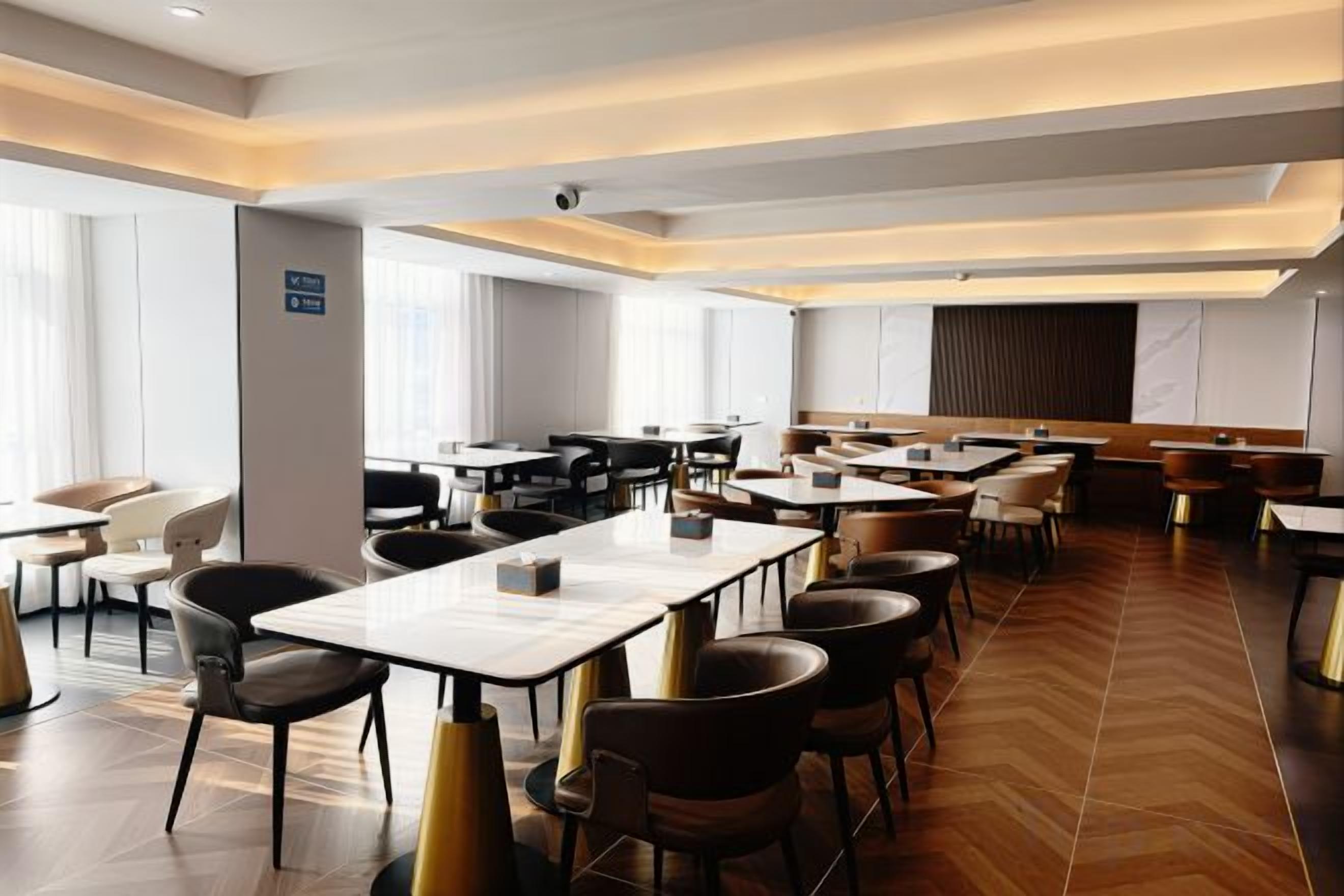 A hotel dining area with multiple tables and chairs, a bar area, and a view of the city.