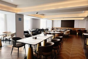 Un espace de restauration d’hôtel comprenant plusieurs tables et chaises, un bar et une vue sur la ville.