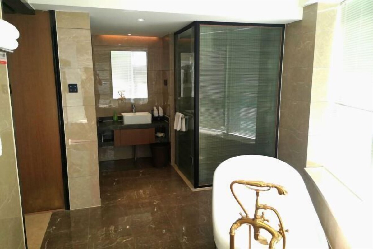 A modern bathroom with a glass shower enclosure, a white bathtub, and a vanity with a sink and mirror.
