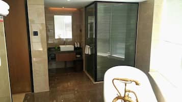 A modern bathroom with a glass shower enclosure, a white bathtub, and a vanity with a sink and mirror.