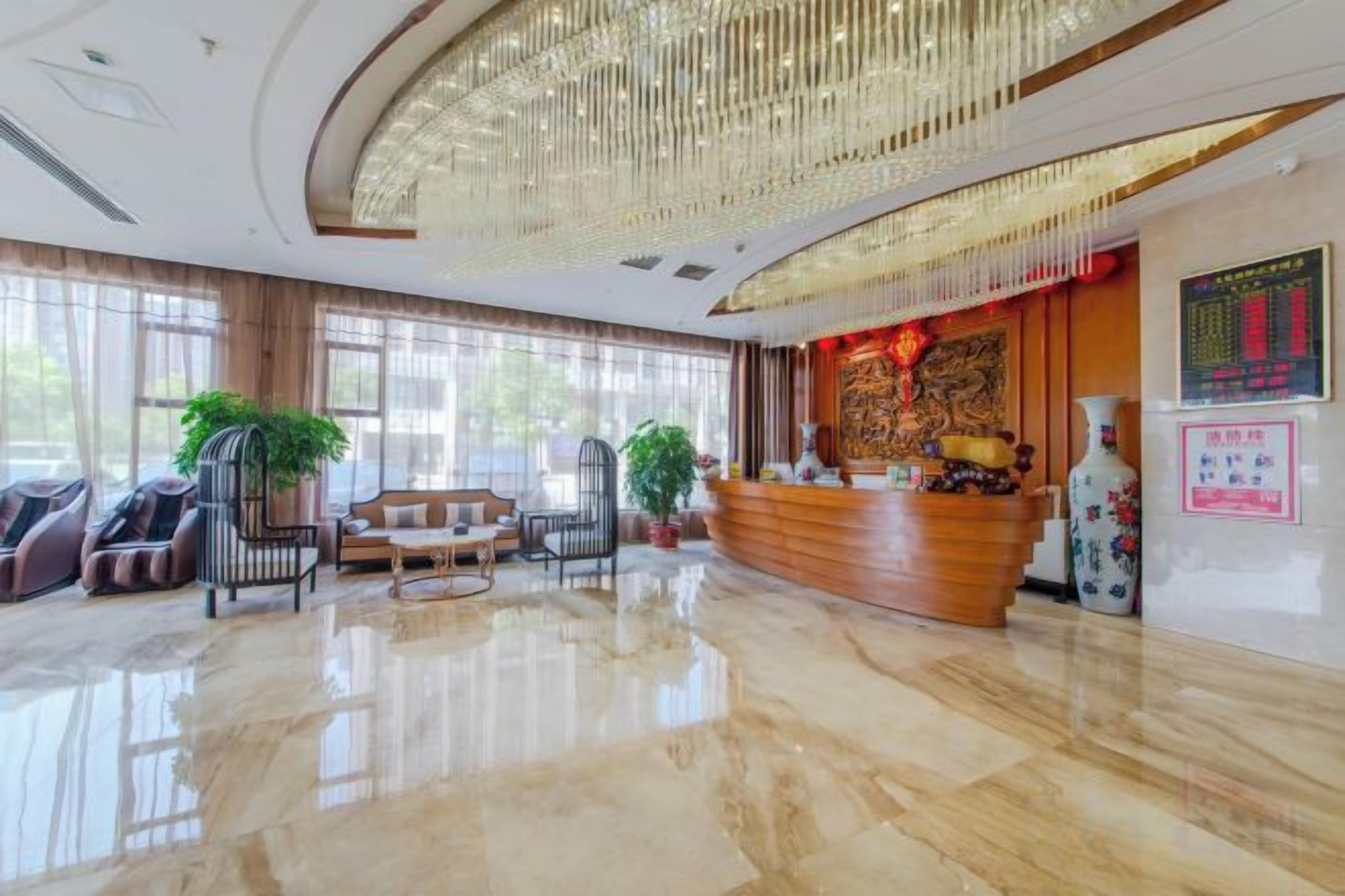 A hotel lobby with a reception desk, seating area, and large windows.