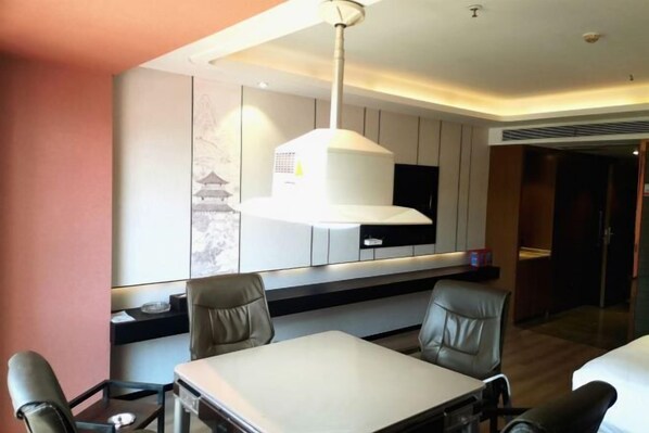 A modern dining area with a table and chairs, a large pendant light, and a wall-mounted TV.