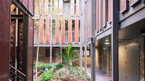 A courtyard with a brick wall, a metal fence, and a small garden area with plants. - The City Song 1 bedroom apartment in Rotherhithe (London)
