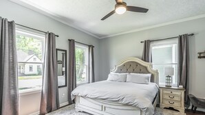 Een slaapkamer met een groot bed, een plafondventilator en uitzicht op buiten.