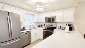 A modern kitchen with white cabinets, stainless steel appliances, and a central island.