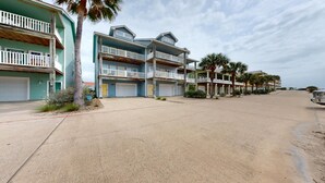 Un quartier résidentiel en bord de mer, avec des immeubles à plusieurs étages, des balcons et une rue sablonneuse.