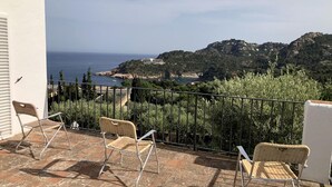 A terrace with wicker chairs overlooking a coastal landscape with a view of the sea and hills. - Casa Illa Blanca, Aiguablava, Begur (Begur)