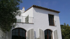 A two-story building with white walls, large arched windows with shutters, and a tiled roof. - Casa Illa Blanca, Aiguablava, Begur (Begur)