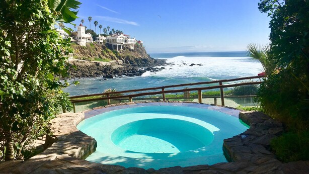 Ein Pool mit Blick auf den Ozean und ein Gebäude am Hang.