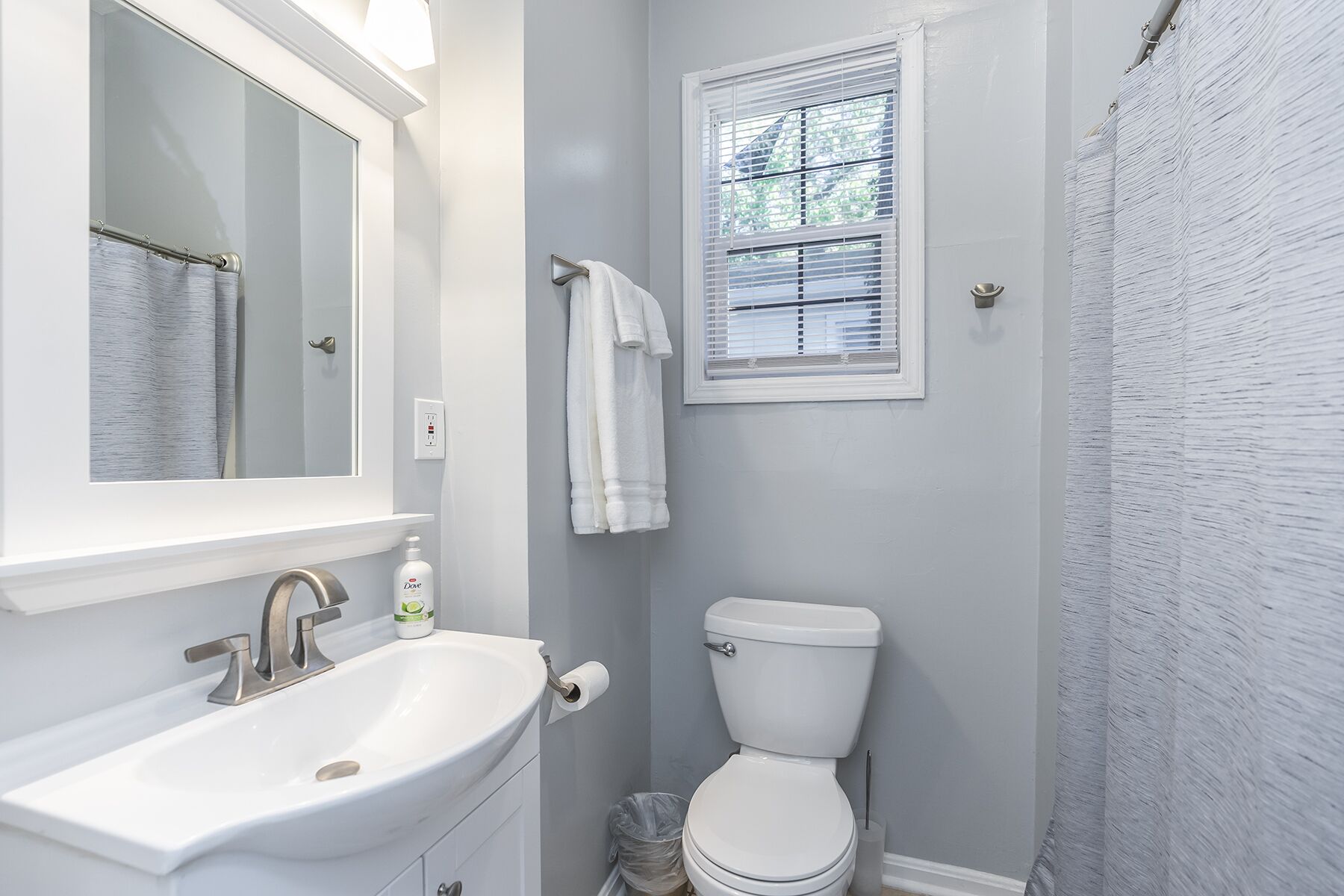 Une salle de bain avec un lavabo blanc, des toilettes et un rideau de douche.