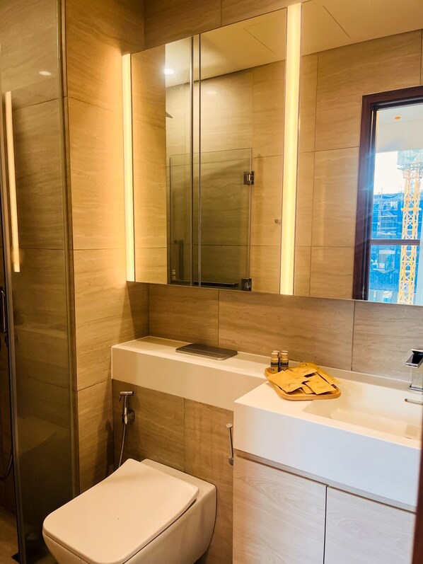 Un baño moderno con cabina de ducha de vidrio, inodoro blanco y tocador con espejo.