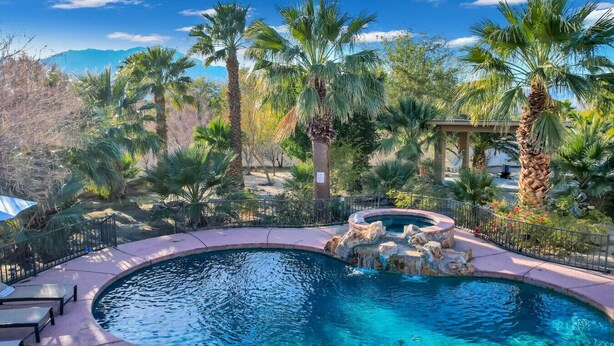 A swimming pool with a hot tub, surrounded by palm trees and a mountainous backdrop. - Natural Springs-2 acre, Games+karaoke, fit,views. (Riverside County)