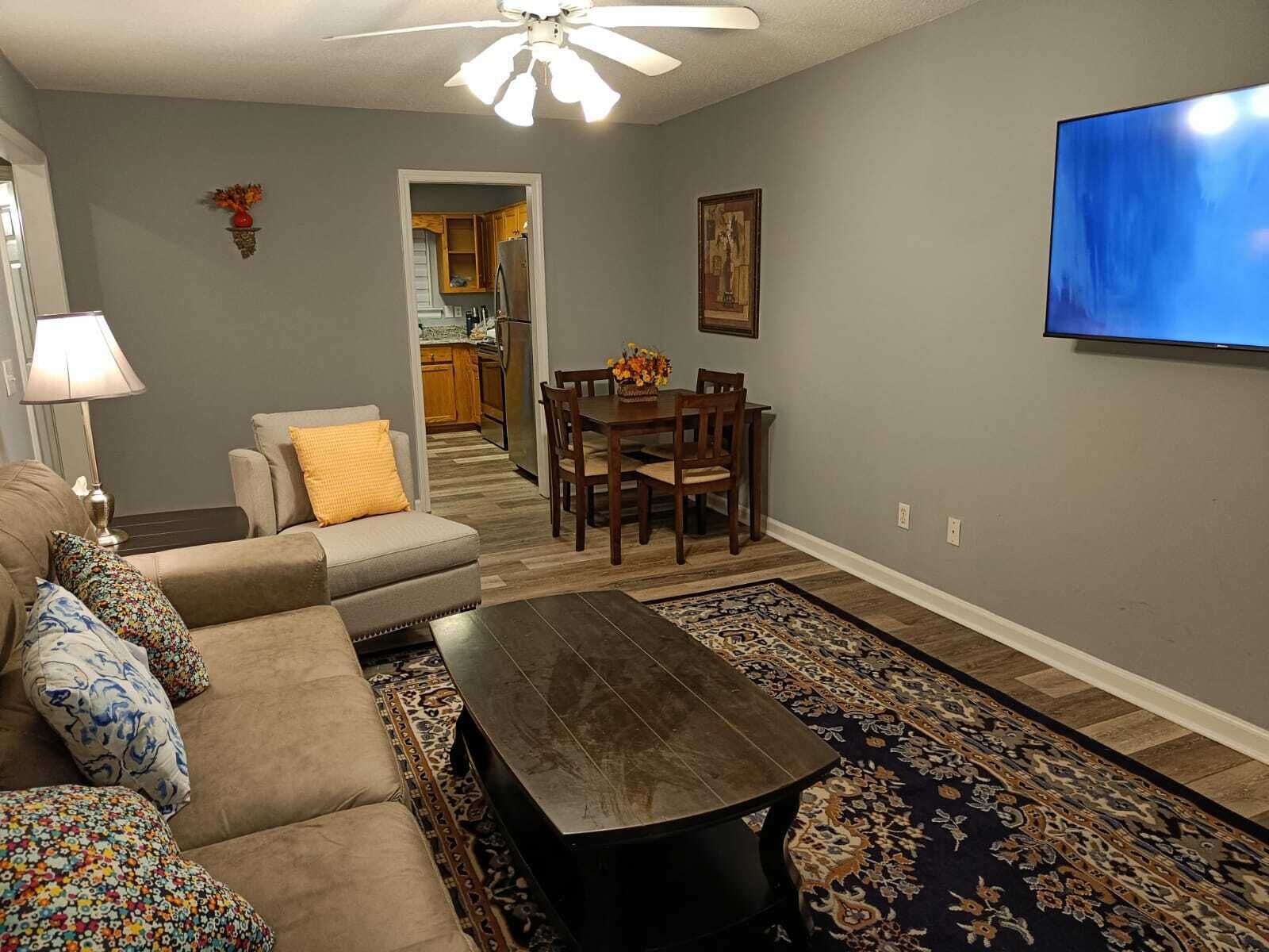 Een woonkamer met een bank, salontafel en een televisie aan de muur.