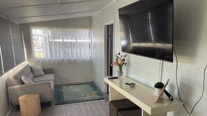 Un saló modern amb un sofà, una taula de centre, una televisió penjada a la paret i una petita catifa.