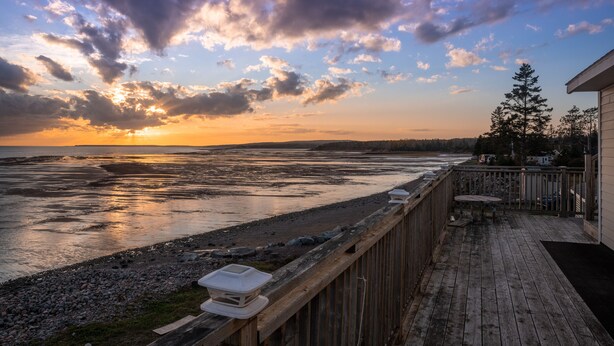 A wooden deck with a view of a sunset over a river. - 10M From the Ocean! Upper Suite with Amazing Views - Highest Tides in the World (Five Houses)