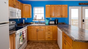 A kitchen with wooden cabinets, a white stove, and a window with a view. - 10M From the Ocean! Upper Suite with Amazing Views - Highest Tides in the World (Five Houses)