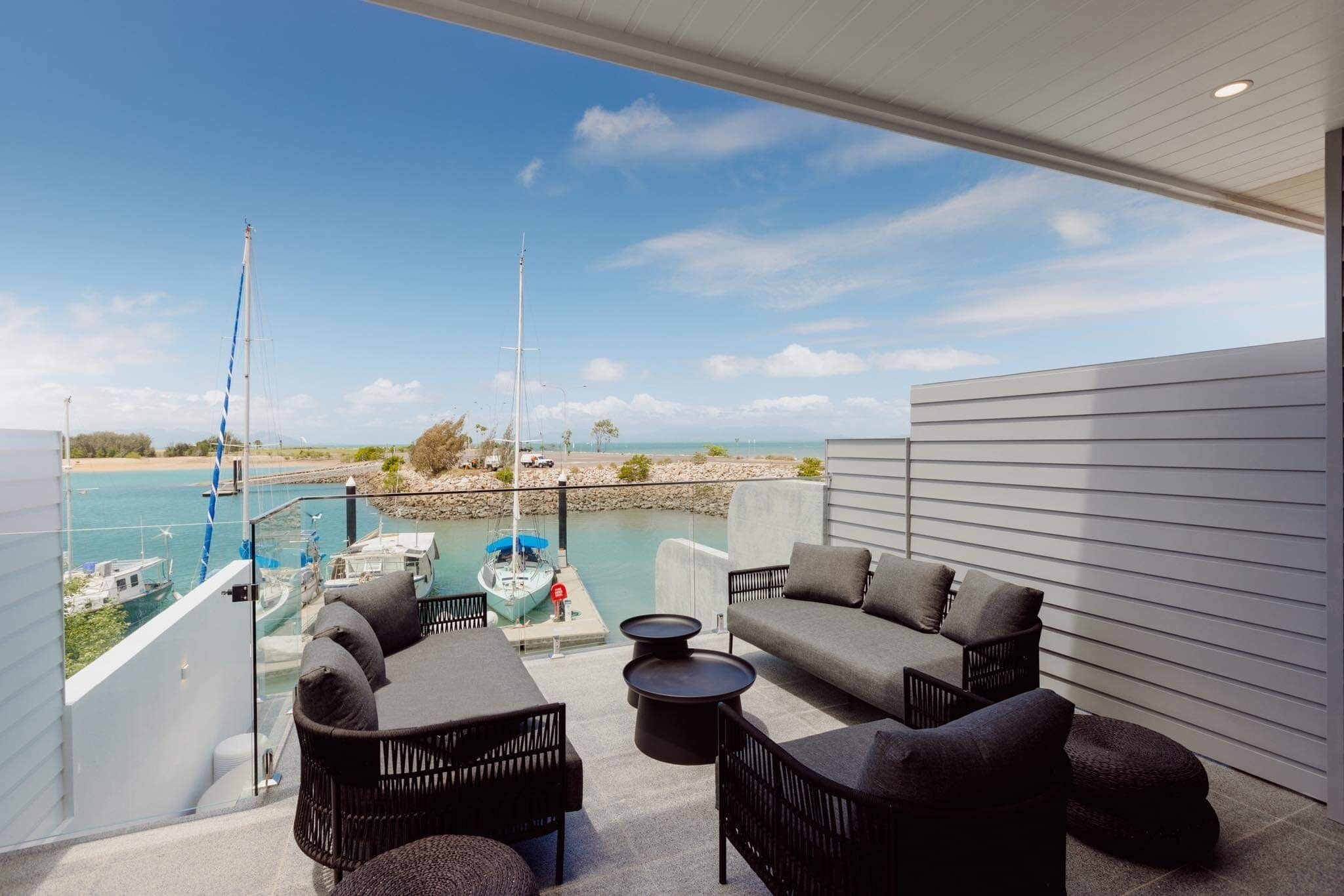Ein Balkon mit Gartenmöbeln, Blick auf den Yachthafen und einem klaren Himmel.