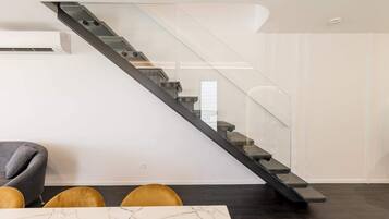 Un interior moderno con una escalera de cristal, una mesa de mármol y un sofá.