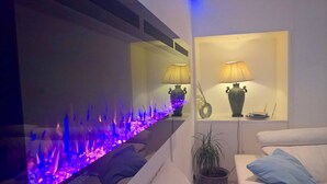 A modern interior with a water feature, two lamps, a sofa, and a potted plant. - Apartment With Pool Near Beach In St Julians (Swieqi)