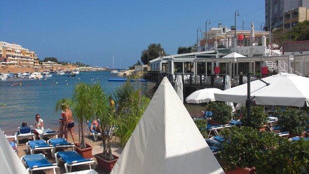A coastal hotel with outdoor seating, a poolside area, and a view of the marina. - Apartment With Pool Near Beach In St Julians (Swieqi)