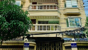 Um edifício de vários andares com varandas, entrada fechada por portão e um letreiro com a inscrição 'Heaven Inn'.