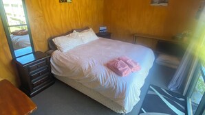 Une chambre à coucher comprenant un lit, une commode, une table de chevet, un miroir et une fenêtre donnant sur un beau paysage.