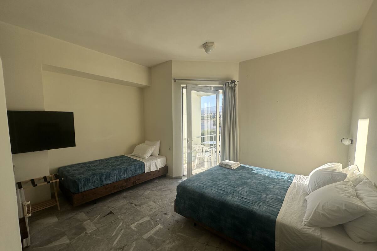 Ein Schlafzimmer mit zwei Betten, einem Fernseher und einem Balkon mit Blick.