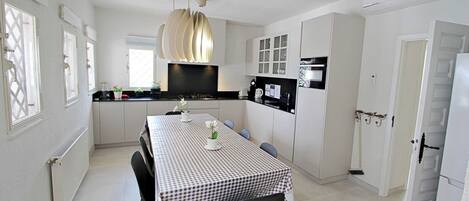A modern kitchen with white cabinets, a black countertop, and a checkered tablecloth.