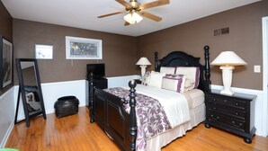 A bedroom with a bed, two bedside tables, a ceiling fan, a window with blinds, and a wall-mounted TV. - State Line Rd near Downtown Q39 BBQ-KUMC. WESTPORT! (Kansas City)