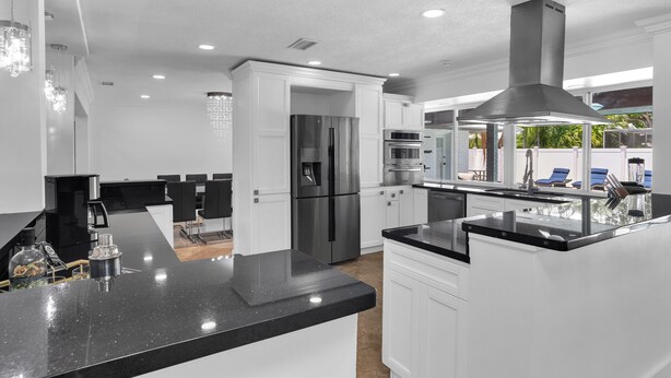 Una cocina moderna con armarios blancos, electrodomésticos de acero inoxidable y una encimera de granito negro.