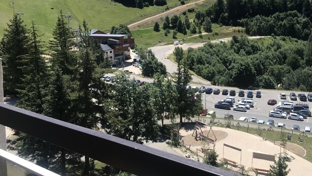 Vista de montanha com teleférico, área de estacionamento e um edifício com placa.