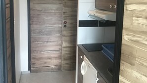Cozinha compacta com porta de madeira, máquina de lavar e bancada com pia.