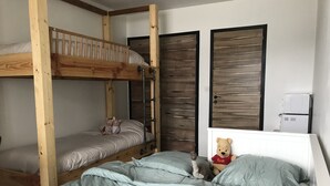 Quarto com cama de solteiro, uma cama individual, um ursinho de pelúcia e um eletrodoméstico branco.