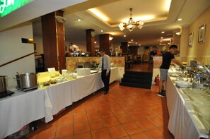 A buffet setup in a hotel dining area with multiple tables covered in white tablecloths, serving dishes, and a variety of food items. - S79 Vuon Saigon Hotel & Spa (Ho Chi Minh City)