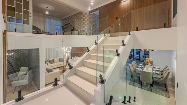 A spacious, multi-level interior with a glass staircase, modern furnishings, and a dining area. - Elegant 4BR Home w/ Private Pool (Santiago De los caballeros)