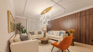 A modern living room with a beige sofa, a round coffee table, and an orange armchair. - Elegant 4BR Home w/ Private Pool (Santiago De los caballeros)
