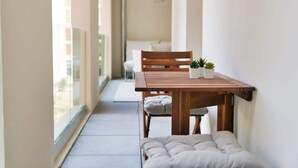 A narrow balcony with a wooden table, two potted plants, and a cushioned bench. - Le Fonction, furnished 4*, boxed parking (Aix-en-Provence)