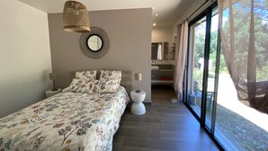 A bedroom with a bed, a hanging light, a round mirror, and a bathroom with a shower and sink. - Villa Olivia 10 minutes from Palombaggia without traffic jams (Porto-Vecchio)