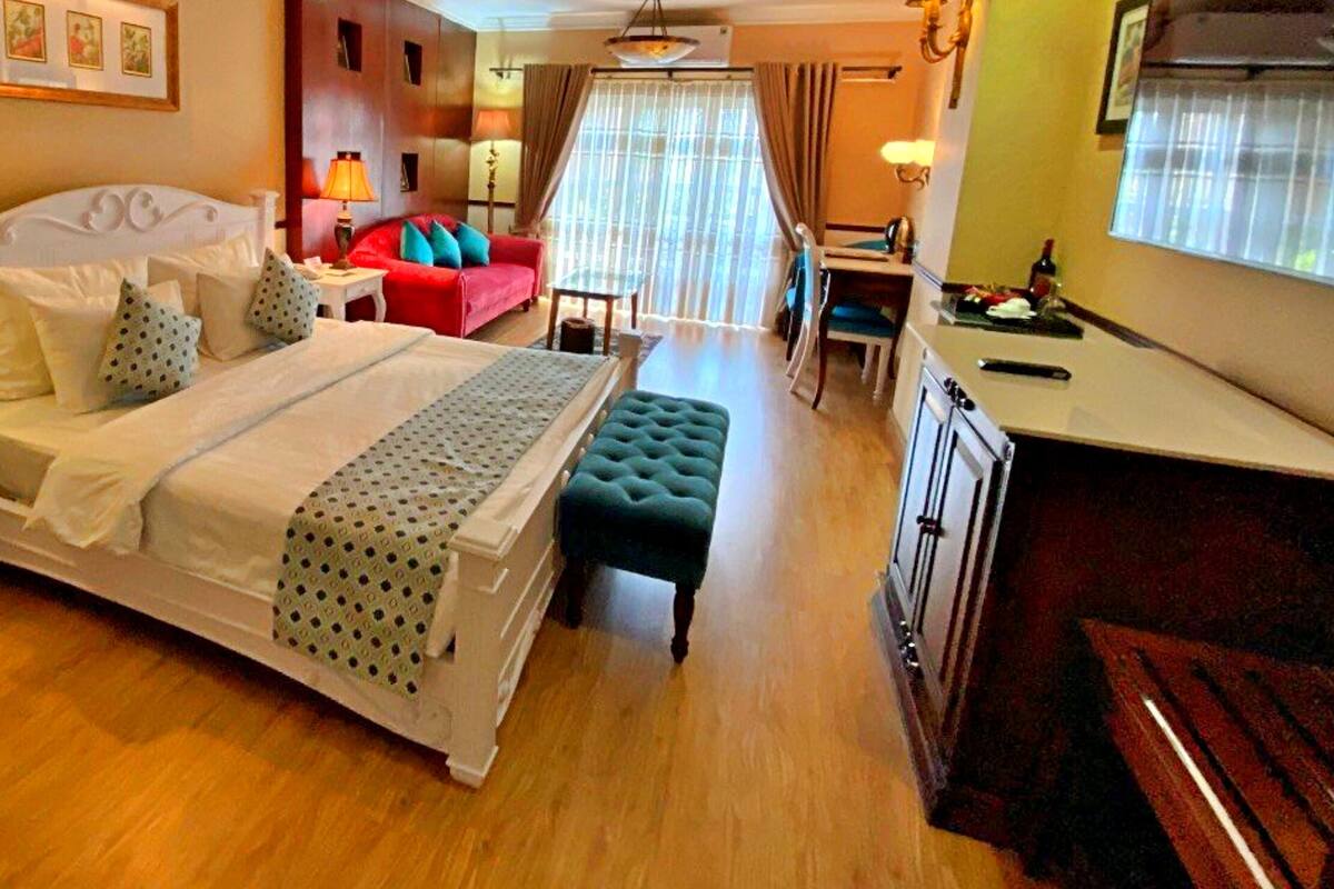 Une chambre d’hôtel comprenant un lit, un bureau, une chaise, un canapé et une table à manger.