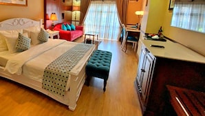 A hotel room with a bed, a desk, a chair, a sofa, and a dining table.