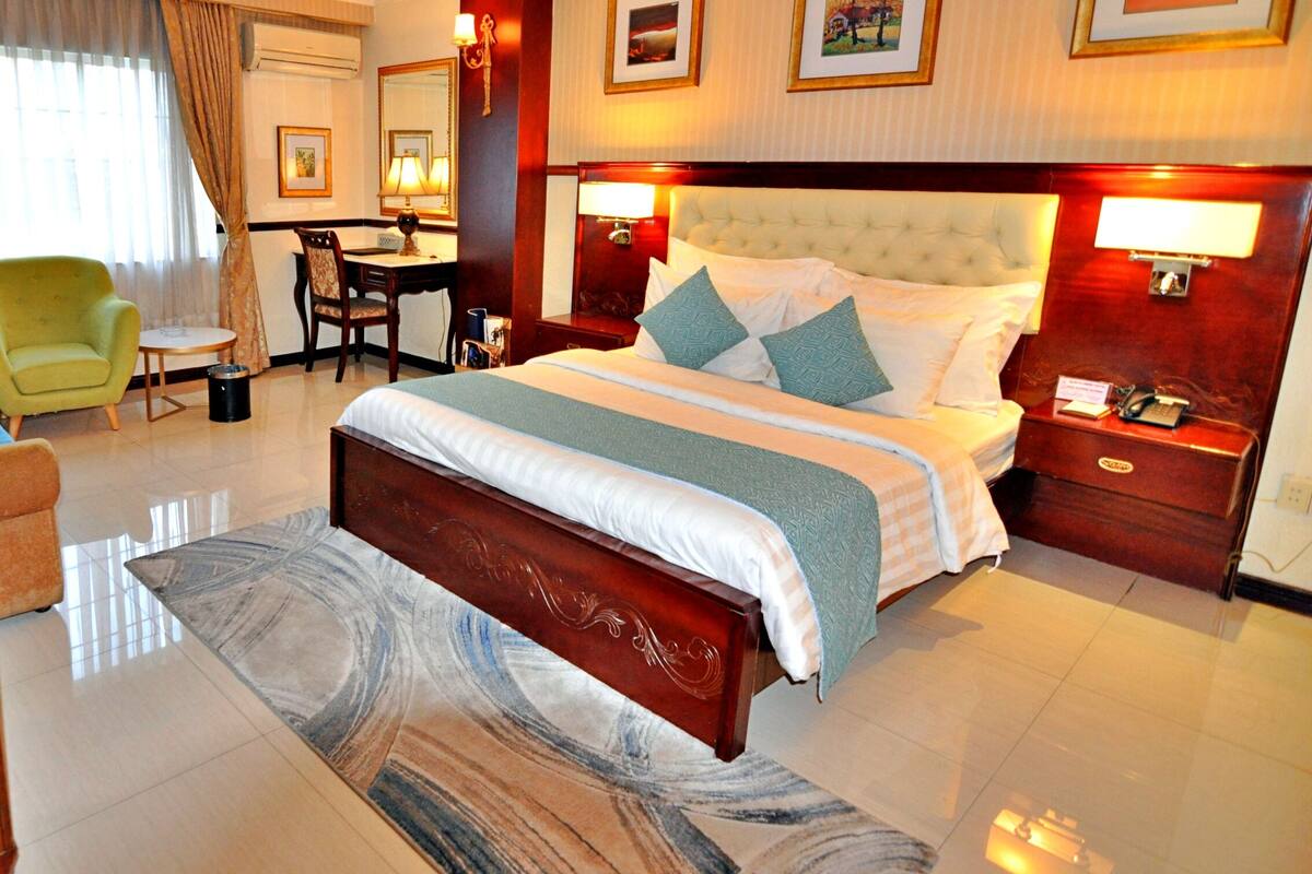 Une chambre d’hôtel avec un grand lit, un bureau, une chaise et une petite table.