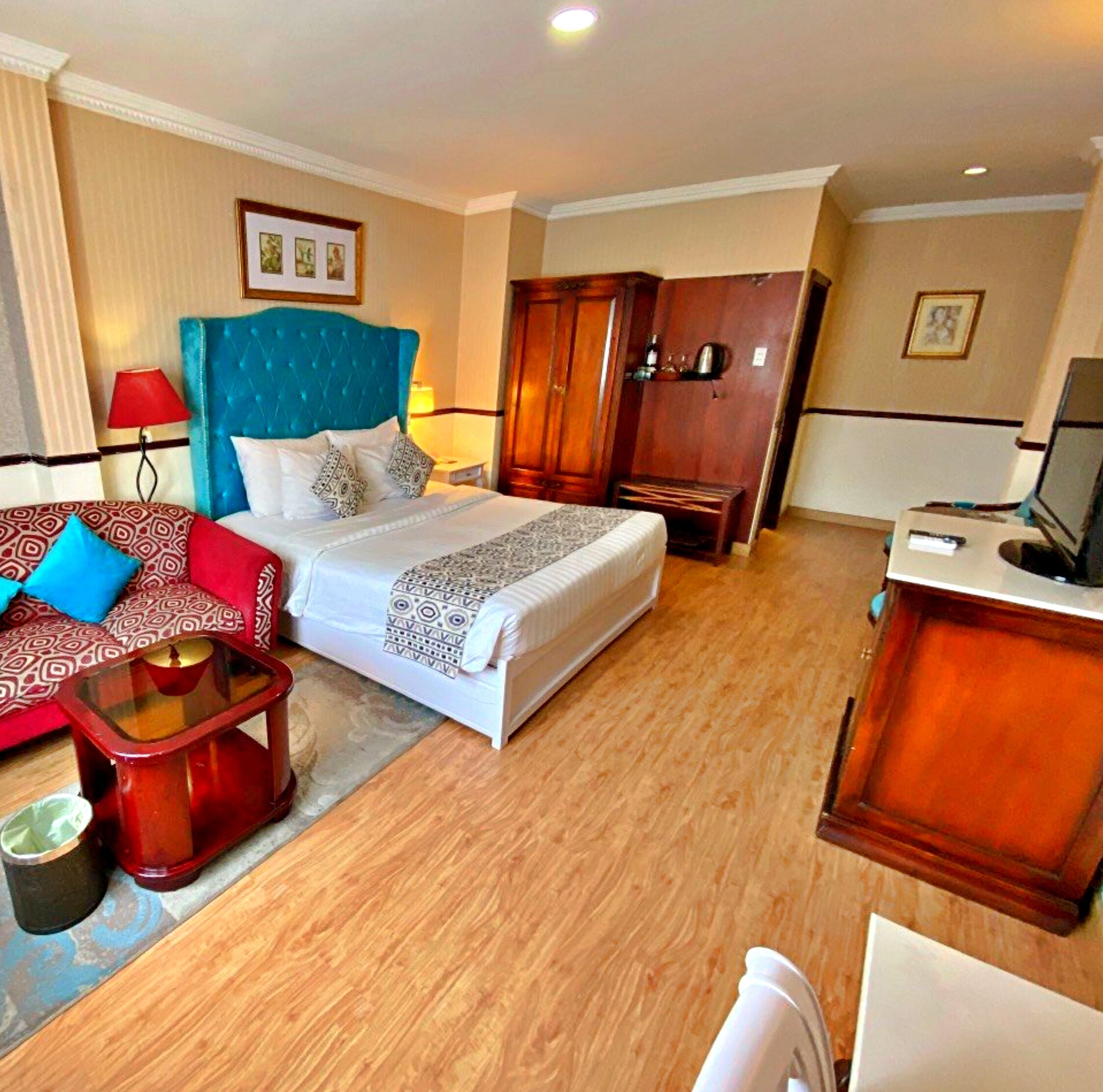 A hotel room with a large bed, a desk, a wardrobe, and a sofa.