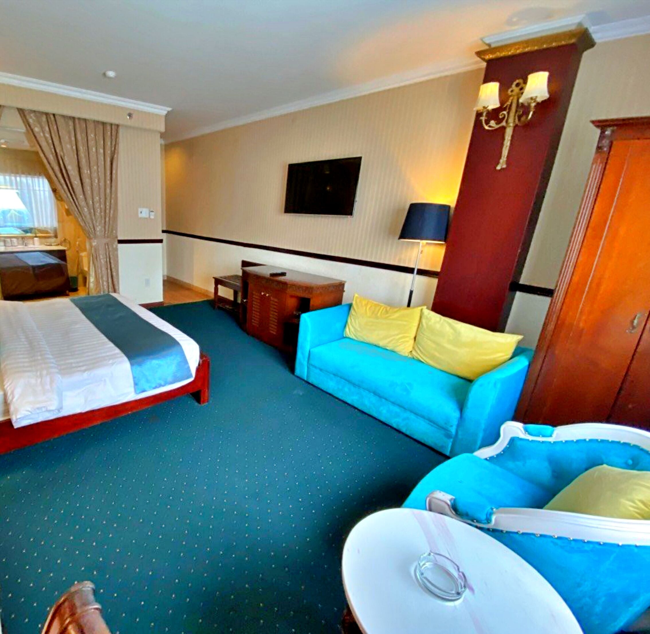 A hotel room with two beds, a sofa, a desk, and a TV.