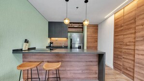 Une cuisine moderne dotée d’un îlot central, de deux tabourets de bar et d’un éclairage suspendu.