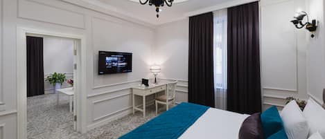 Una habitación de hotel con cama, escritorio, televisor y candelabro.