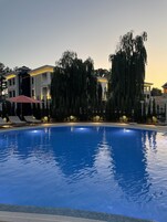 A swimming pool with lounge chairs and a building with classical architecture in the background.